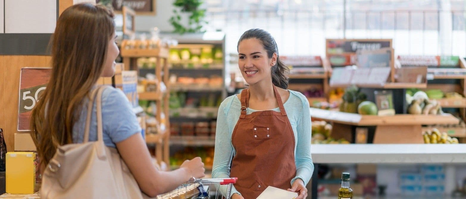 Apprenti vendeuse qui sert une cliente dans l'épicerie