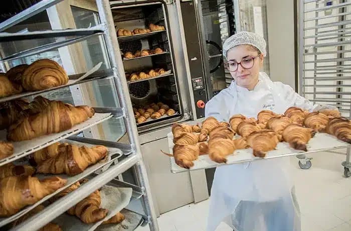 Boulangère qui sort les croissants du four, et qui les met sur le chariot